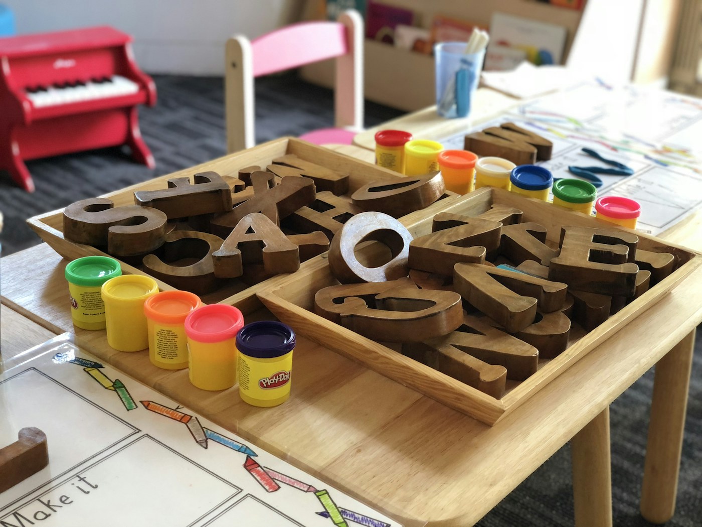 Wooden learning letters and modeling clay arranged on a classroom table